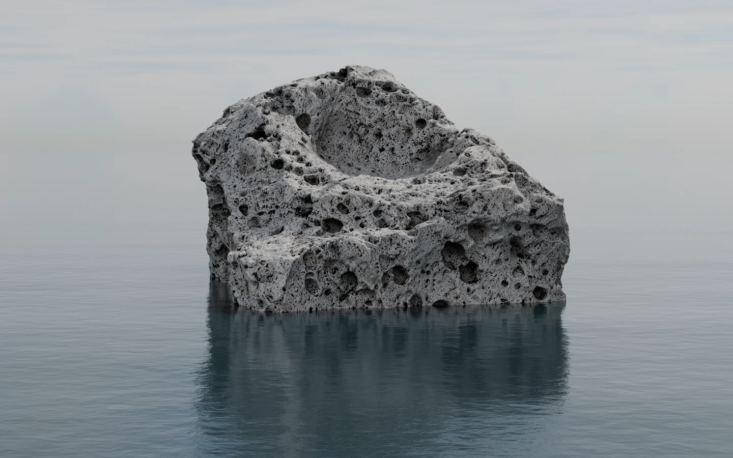 A block of pumice floating alone on a flat grey sea, its reflection beneath it.